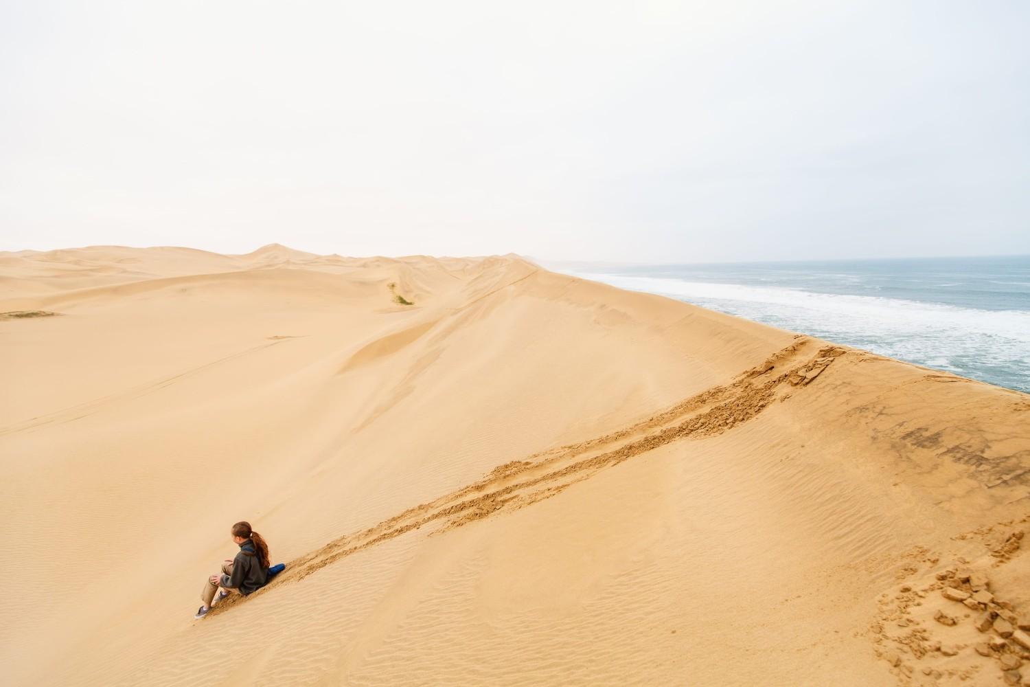 A Girl Dune Surfing At Sandwich Harbour In Namibia