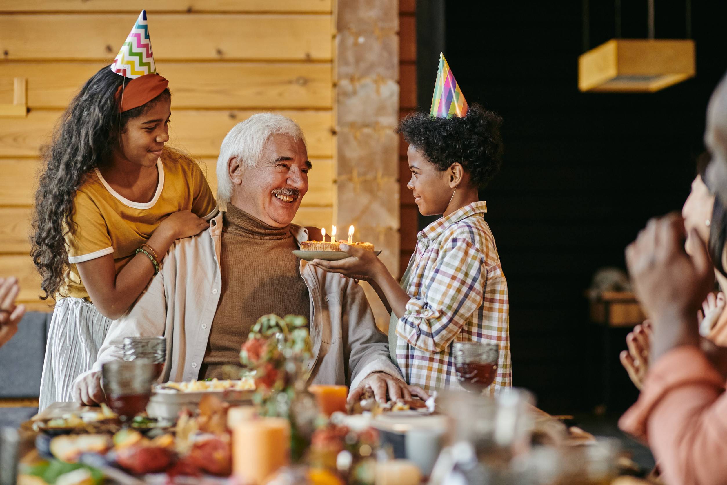 Happy Aged Man Looking At His Interracial Grandson With Birthday