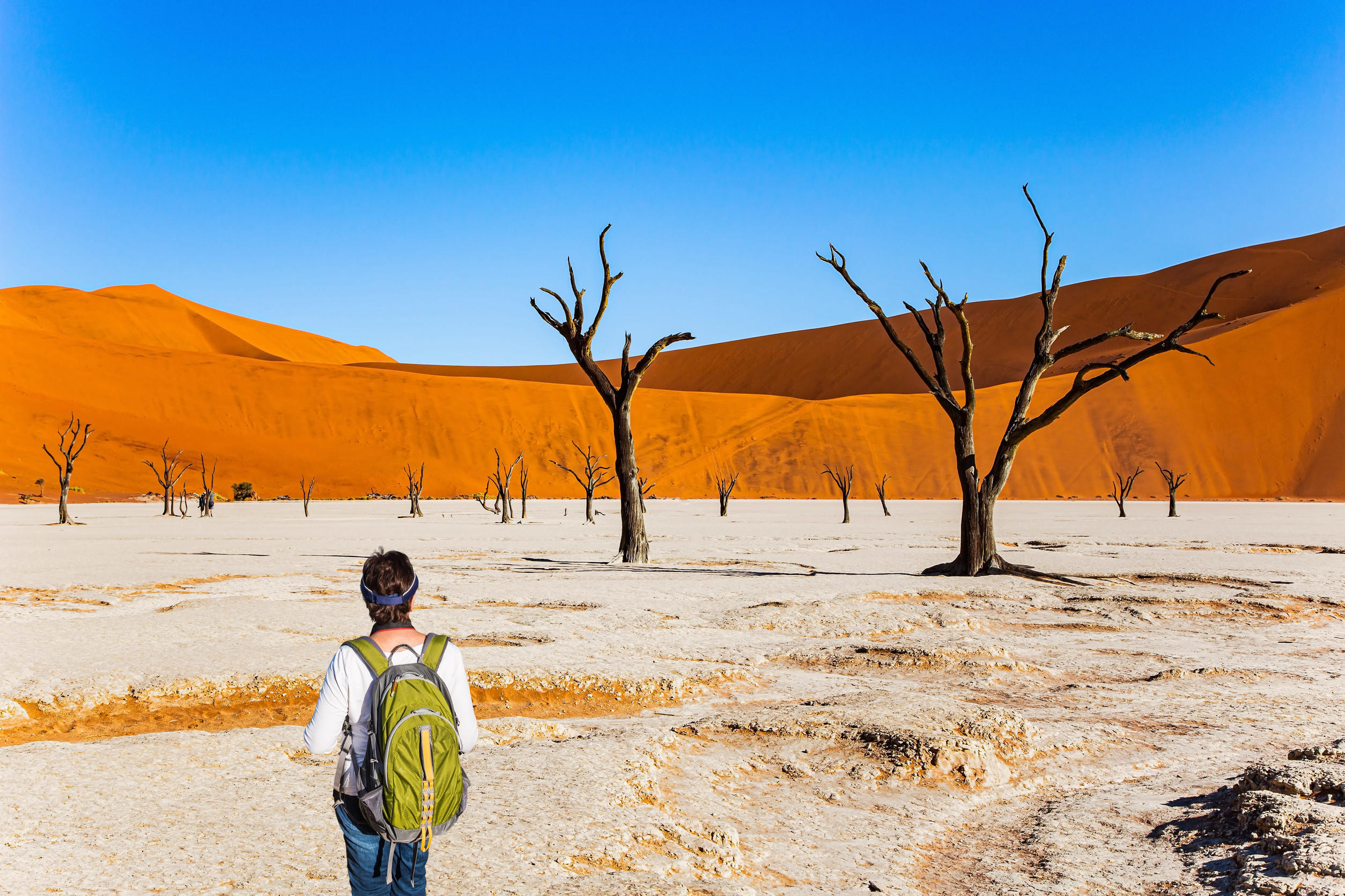 A woman with a green backpack watching the dunes in Namibia
