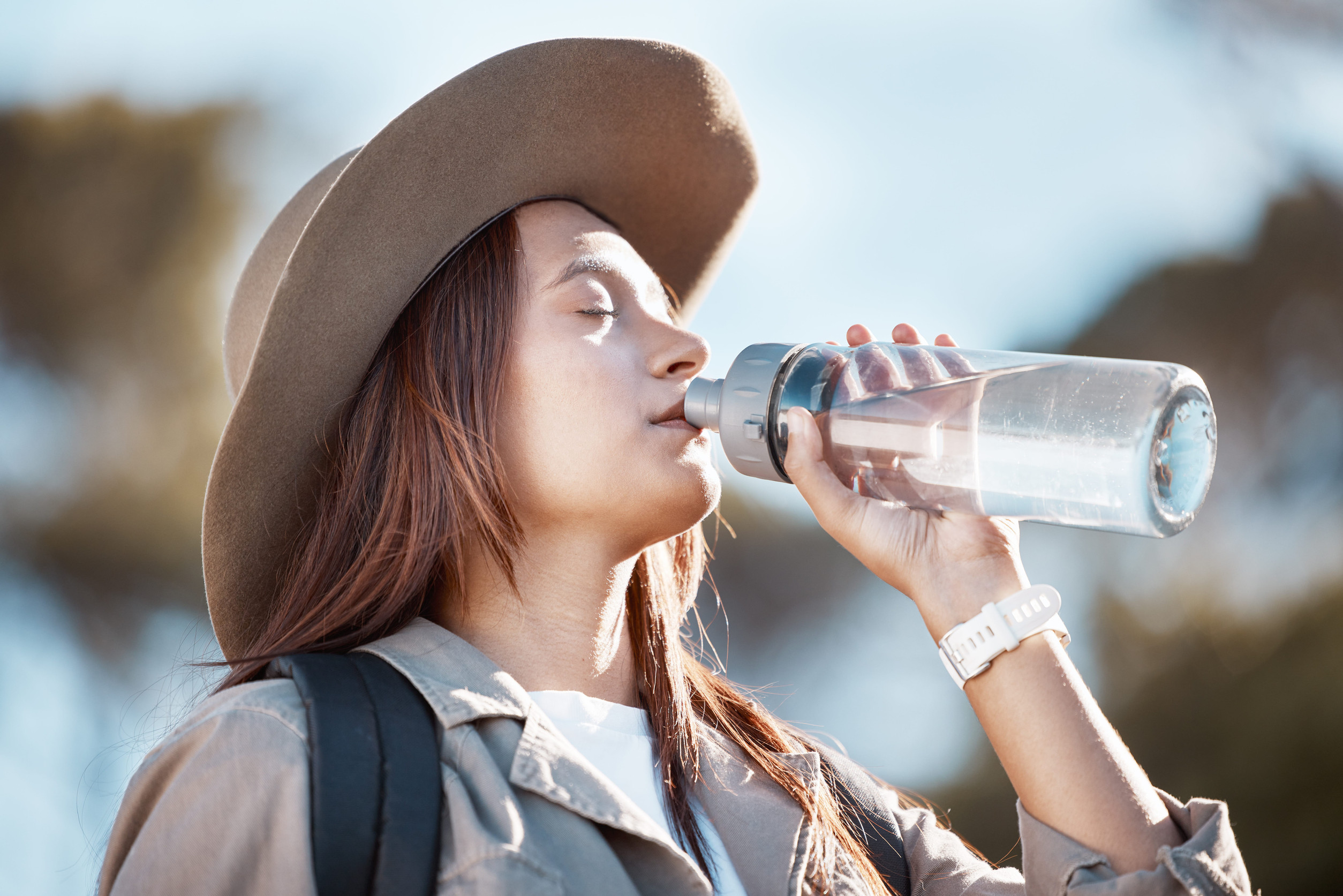 A woman drinking water in the scorching sun to stay hydrated